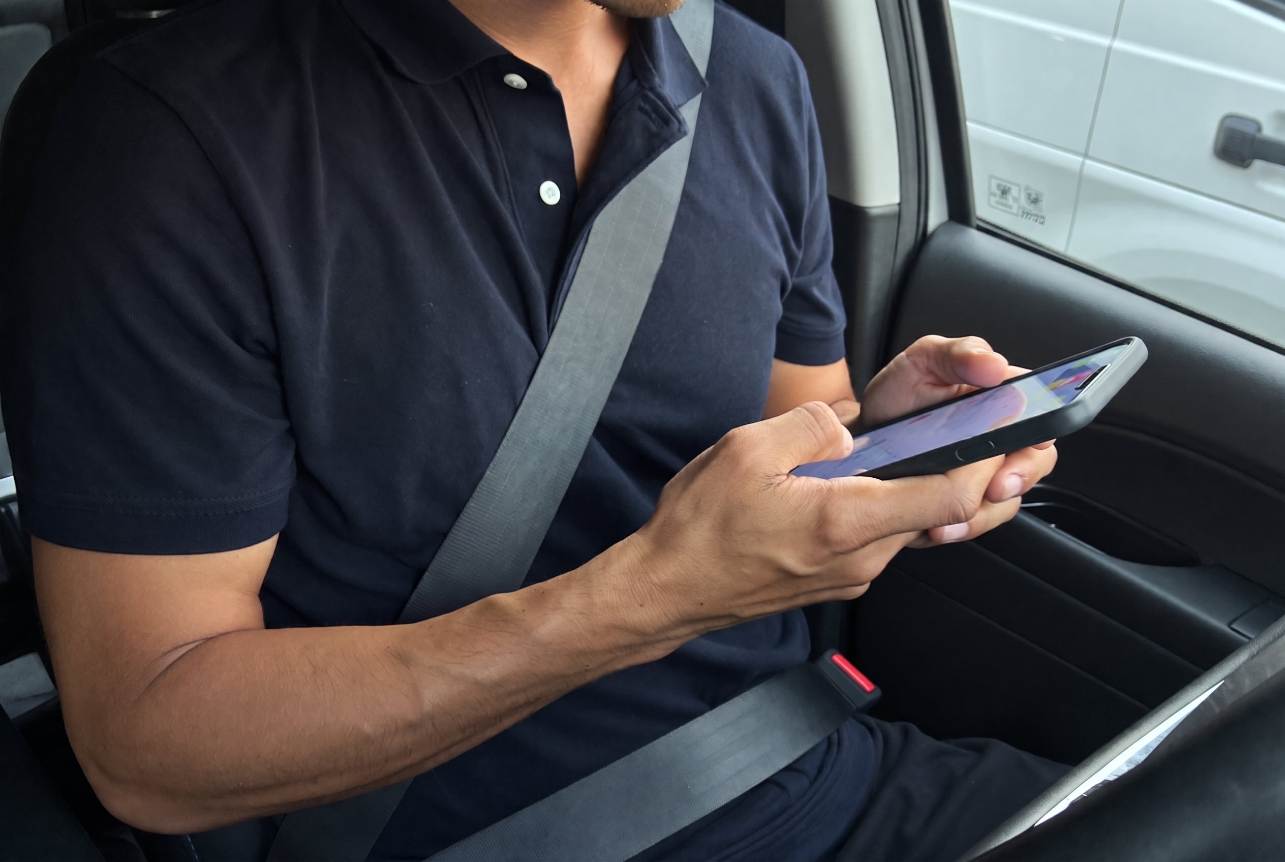 Chauffeur van een bestelbus controleert de rittenregistratie-app op zijn telefoon